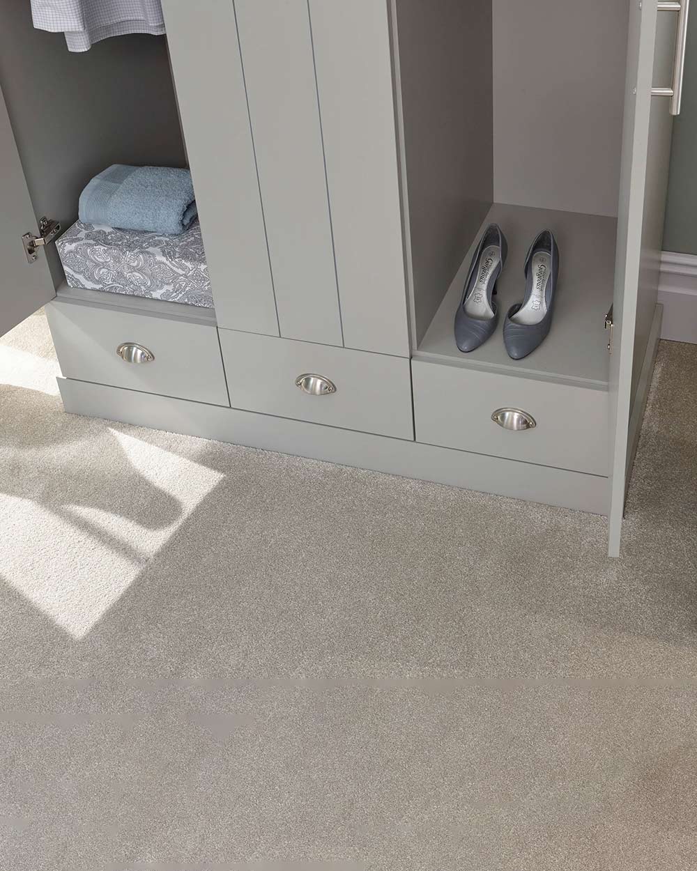 A 3 door wardrobe in modern subtle grey offers ample storage space and elegant brushed steel handles. The wardrobe opens to reveal hanging space and a convenient shelf. It also features three drawers with cup handles. The muted grey colour complements any interior style and contrasts with the oak-effect top. The wardrobe is aesthetically pleasing and sturdy, with a deep base plinth. It comes flat packed for self-assembly. Delivery is available only to mainland UK, excluding certain postcodes.
