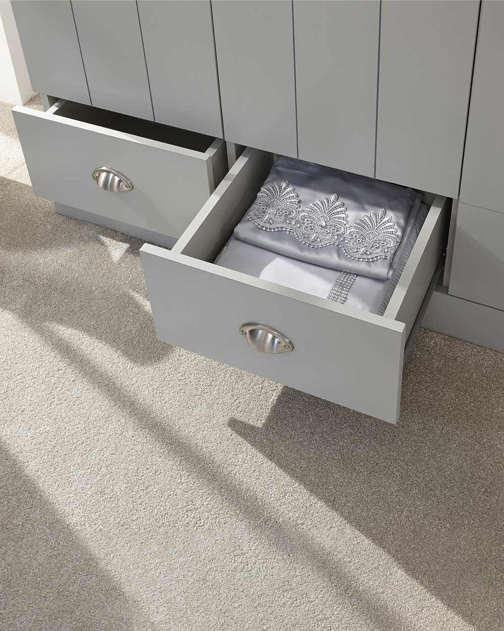 A 3 door wardrobe in modern subtle grey offers ample storage space and elegant brushed steel handles. The wardrobe opens to reveal hanging space and a convenient shelf. It also features three drawers with cup handles. The muted grey colour complements any interior style and contrasts with the oak-effect top. The wardrobe is aesthetically pleasing and sturdy, with a deep base plinth. It comes flat packed for self-assembly. Delivery is available only to mainland UK, excluding certain postcodes.