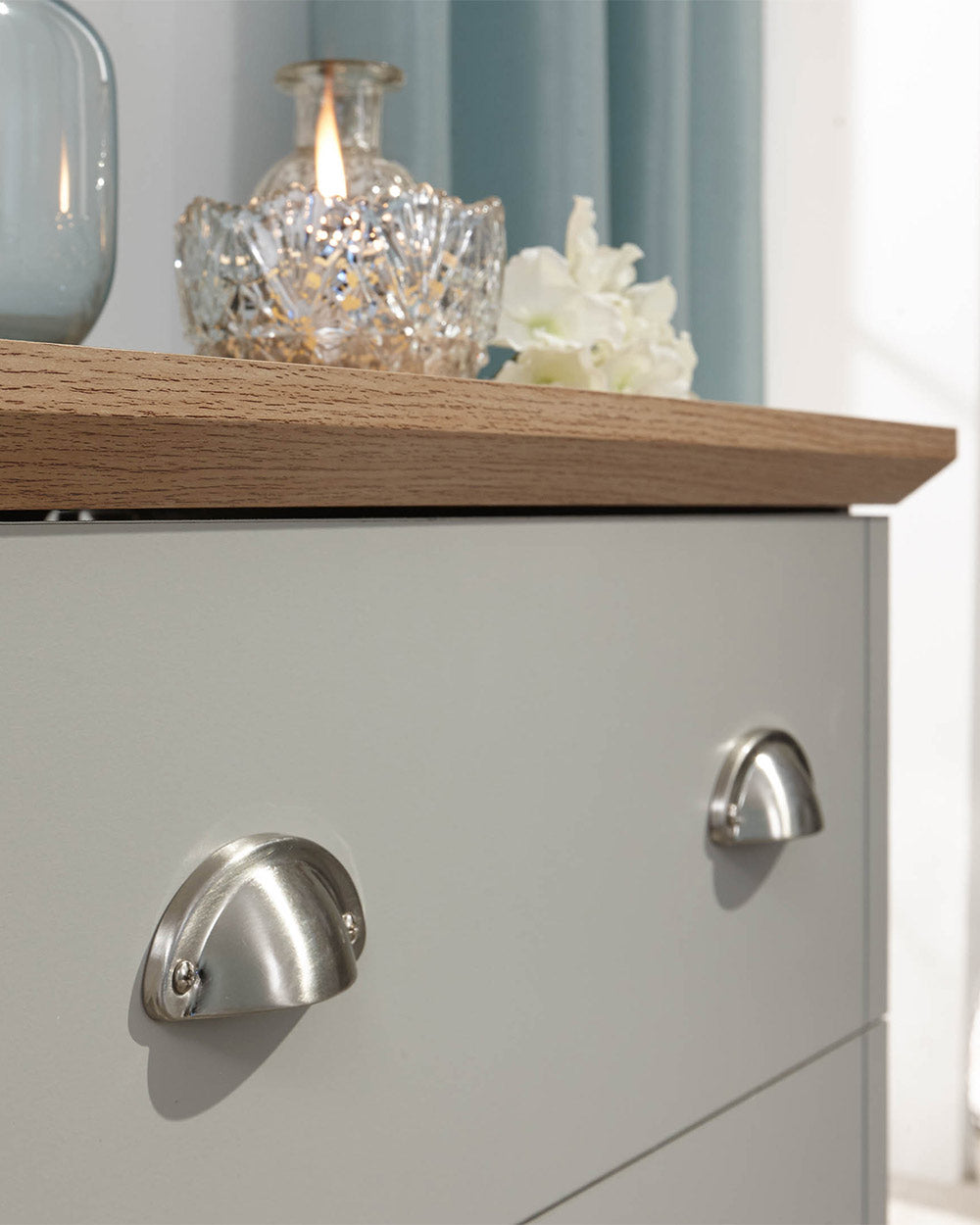 A modern grey chest of drawers with 3 drawers. Generous storage space for clothes and accessories. Features brushed steel cup handles and easy glide metal runners. Sturdy structure with a bevelled oak-effect top. Flat packed for home assembly. Perfect for adding a personal touch to your room.