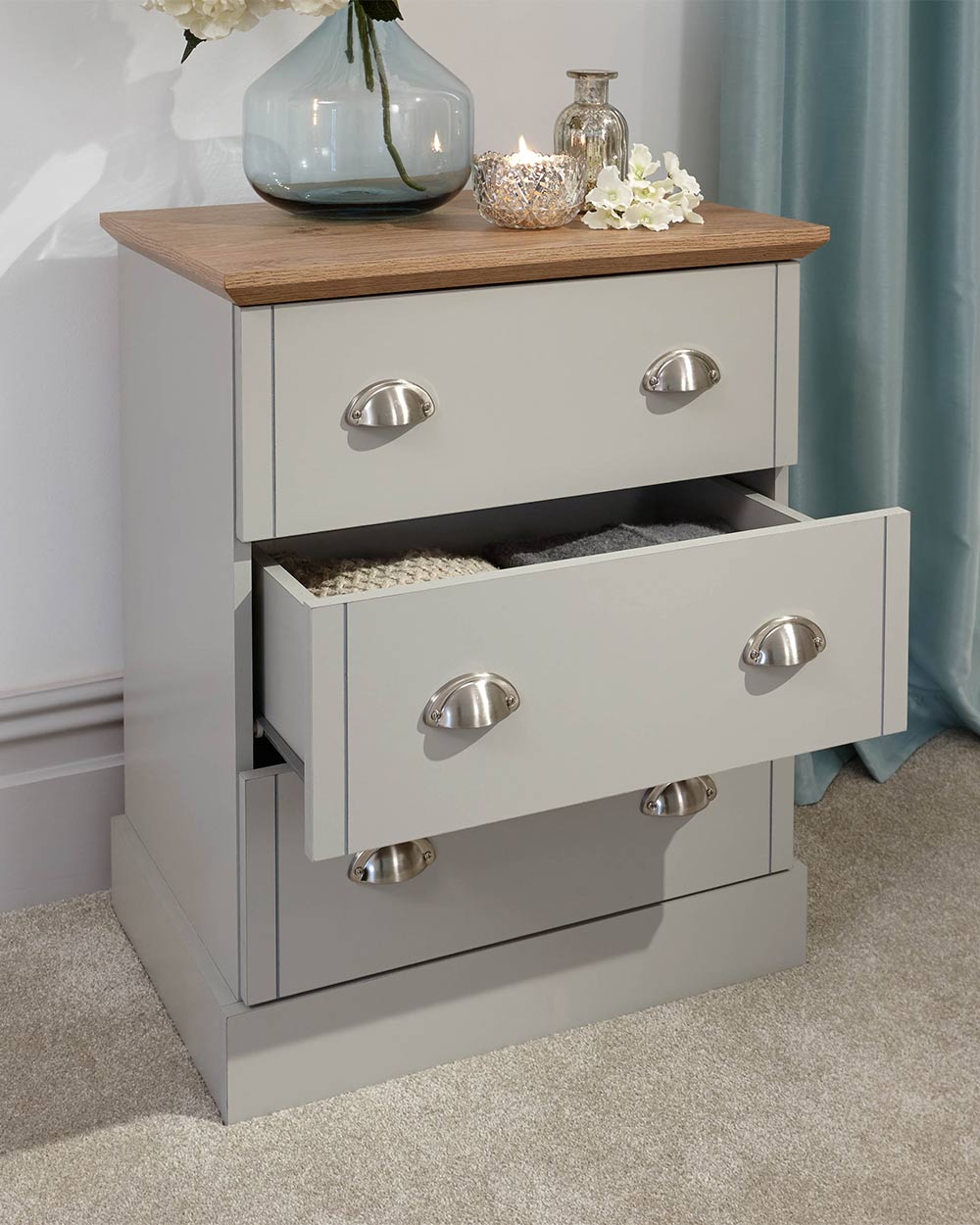 A modern grey chest of drawers with 3 drawers. Generous storage space for clothes and accessories. Features brushed steel cup handles and easy glide metal runners. Sturdy structure with a bevelled oak-effect top. Flat packed for home assembly. Perfect for adding a personal touch to your room.