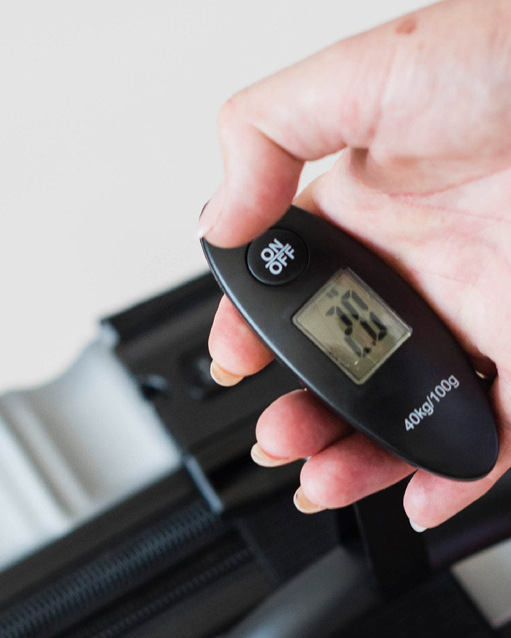 43924luggage scales Navig8 black electronic. Suitcase being weighed, lifestyle image