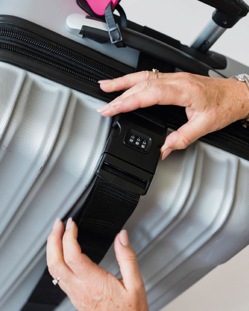 Lifestyle image of a lady setting the padlock code on the combination luggage belt