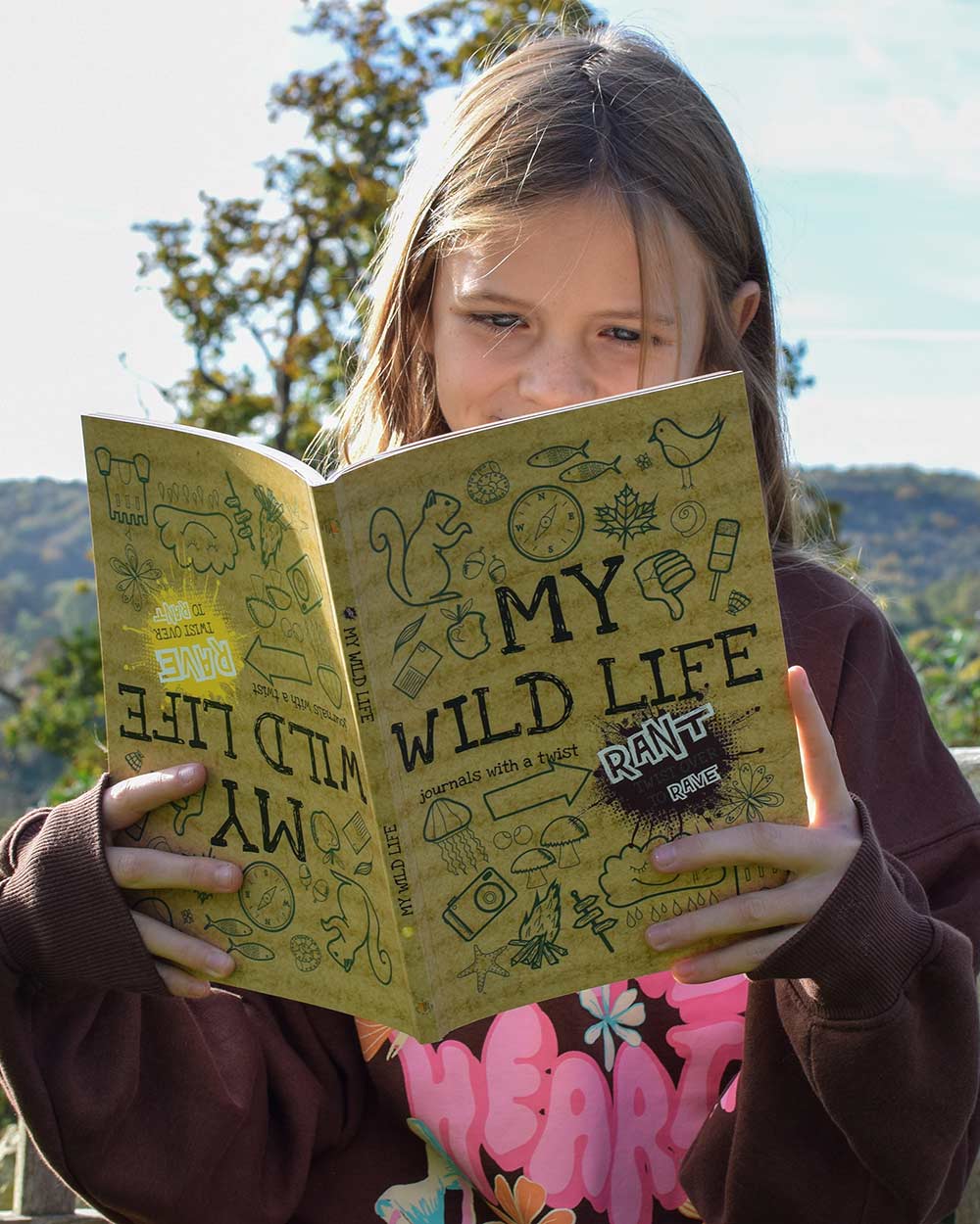 Kids Activity Book Rant & Rave, About My Wild Life. Lifestyle image of a child holding the book outdoors