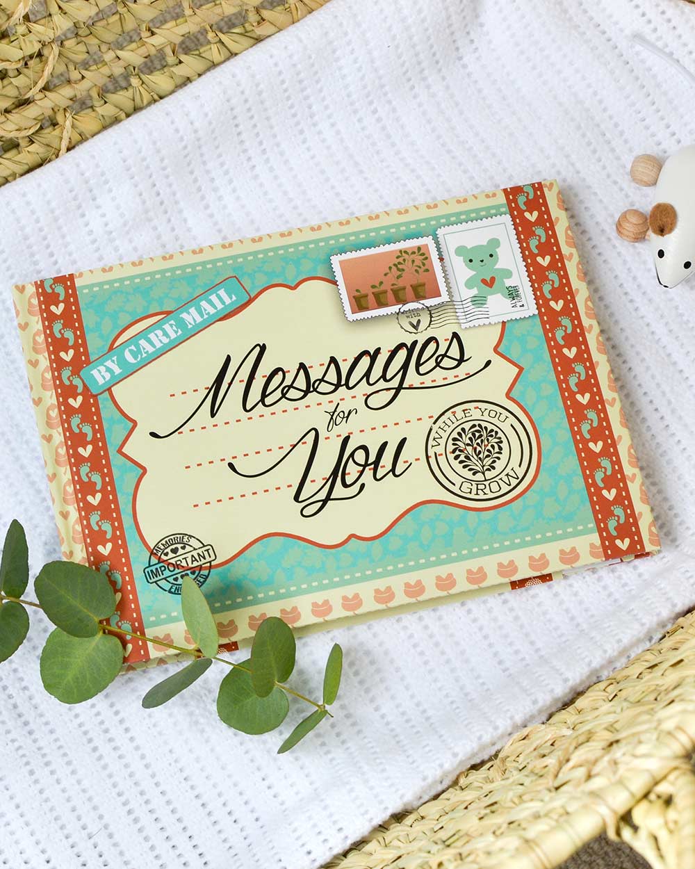 keepsake baby book, messages for while you grow. Lifestyle photo of the front cover of the book, displayed on a baby blanker