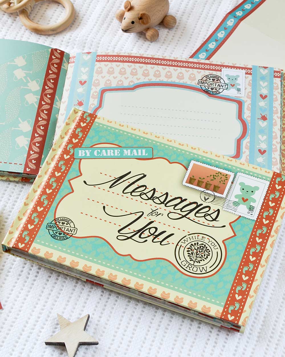 keepsake baby book, messages for while you grow. Lifestyle photo of the front cover of the book and the insides, displayed on a baby blanker