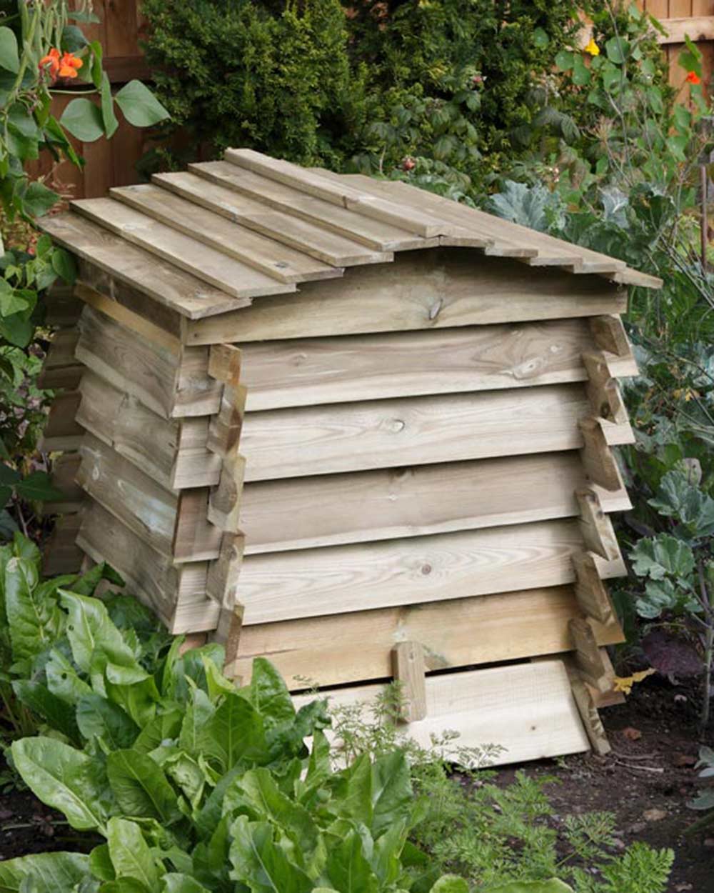 Garden compost bin in the shape of a beehive pictured in someone's garden. Rowlinson beehive composter