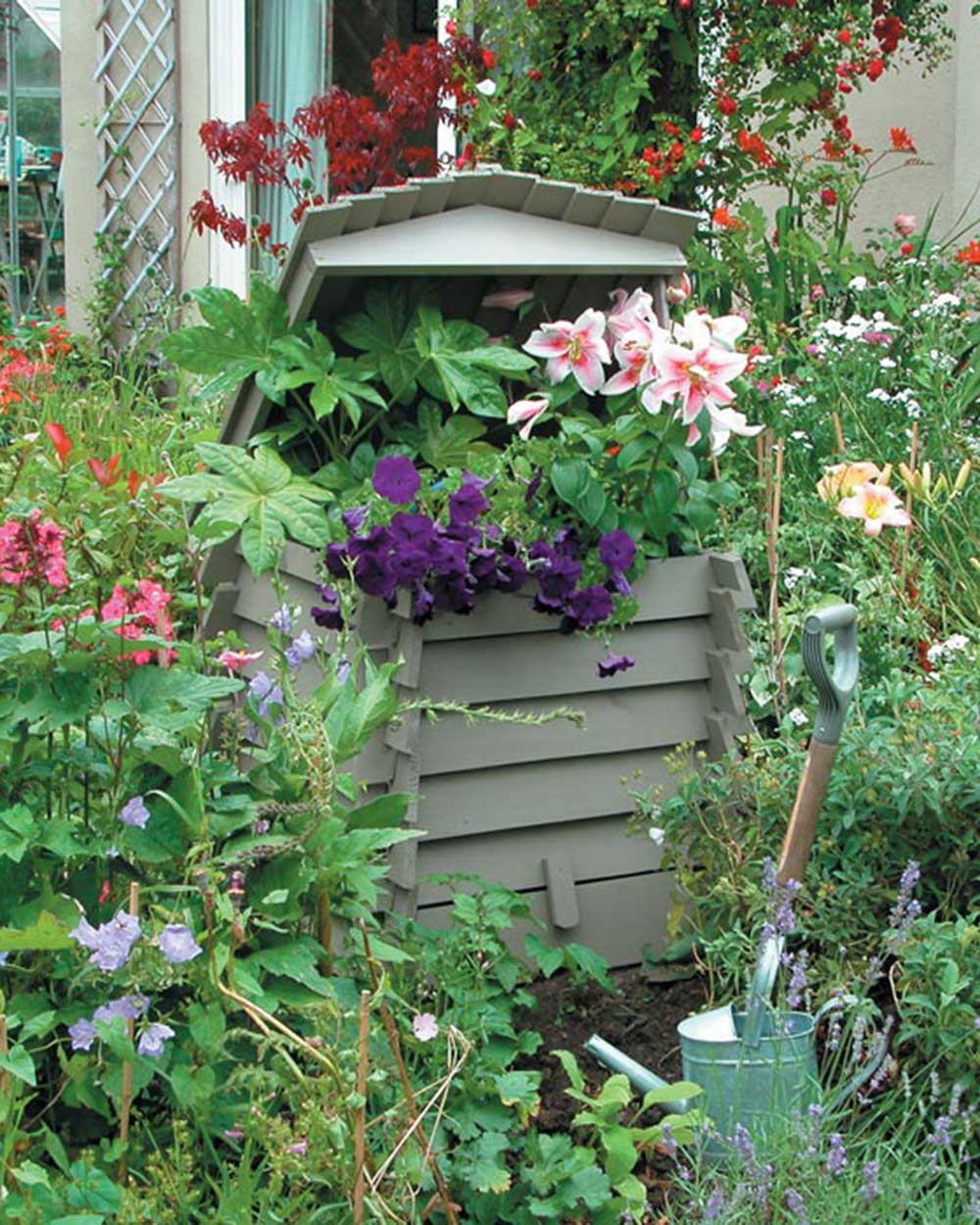 Garden compost bin in the shape of a beehive pictured in someone's garden. Rowlinson beehive composter used as a garden planter in a garden