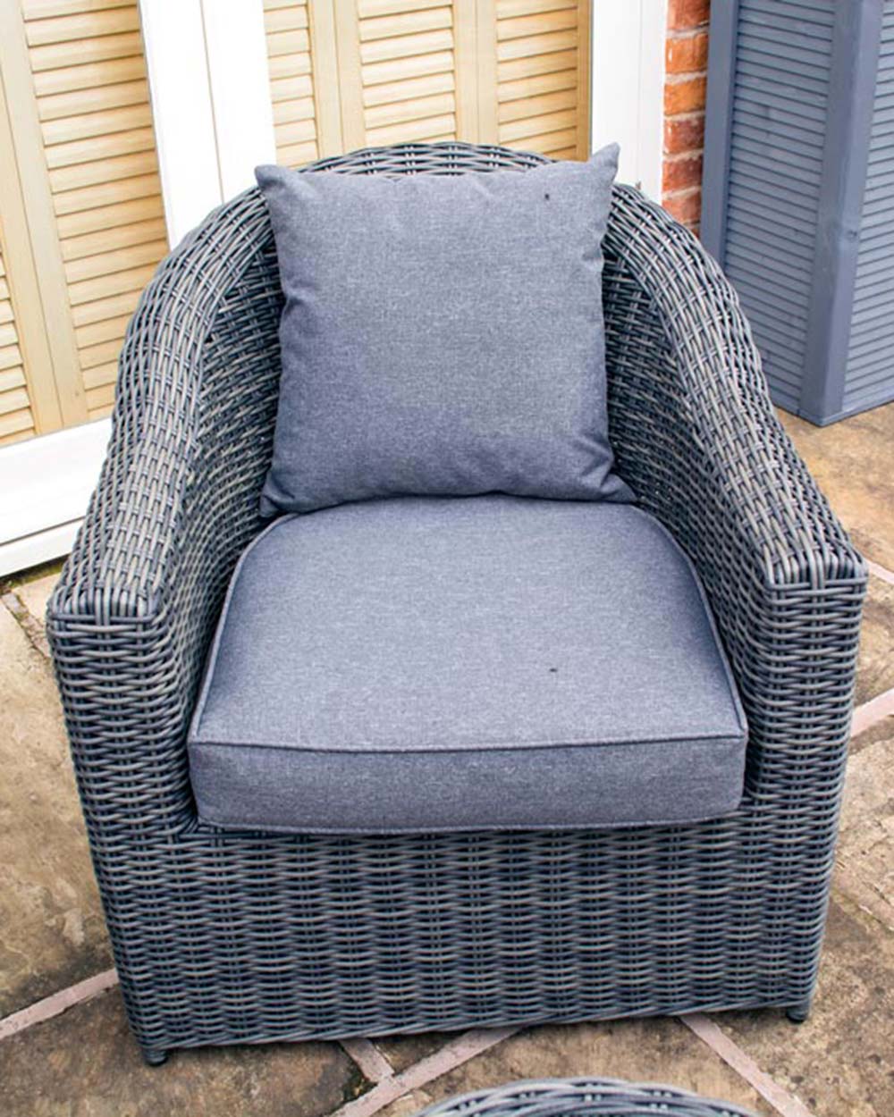 close up of the rattan furniture set displayed on a patio of the arm chair
