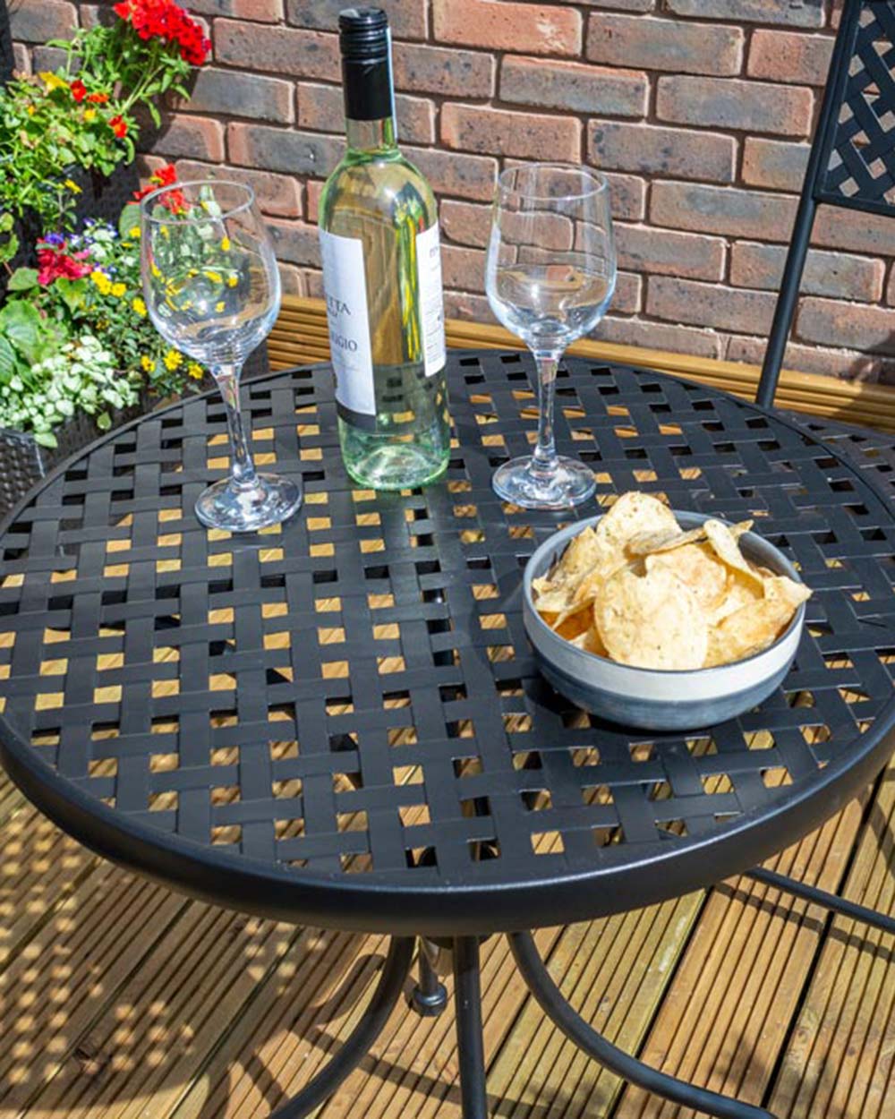garden bistro set black matt lattice pattern Havana Rowlinson. Photo in a garden setting with a bottle of wine and snacks on the table
