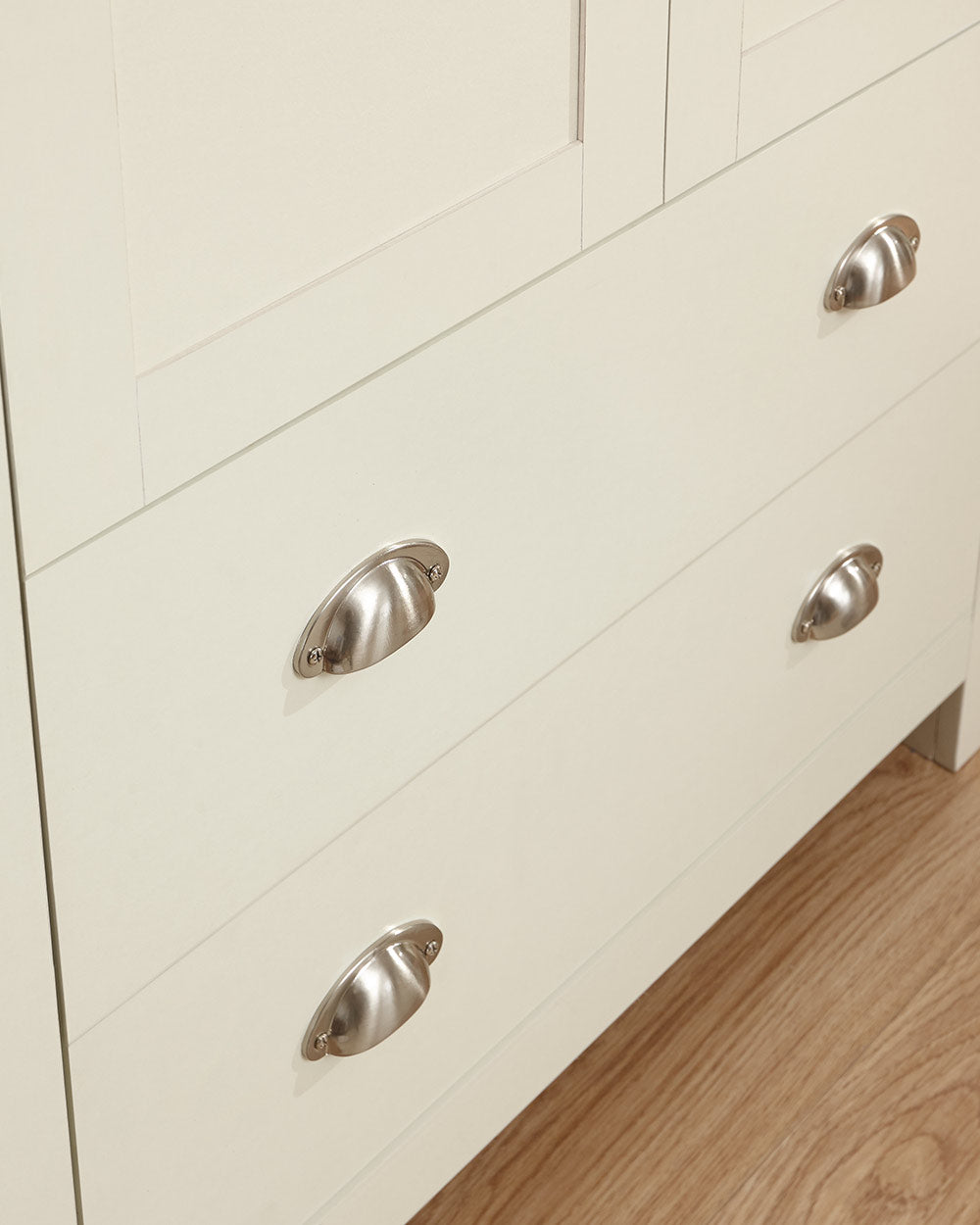 Lancaster shaker style wardrobe in cream with an oak effect top. Displayed in a bedroom setting, close up of the brushed silver handles on the drawers