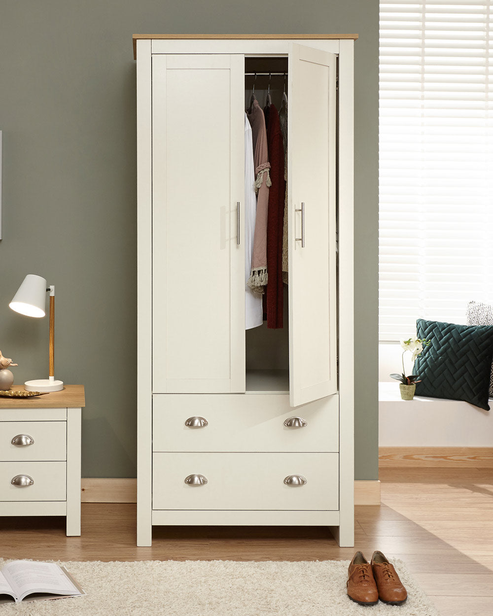 Lancaster shaker style wardrobe in cream with an oak effect top. Displayed in a bedroom setting with the door open