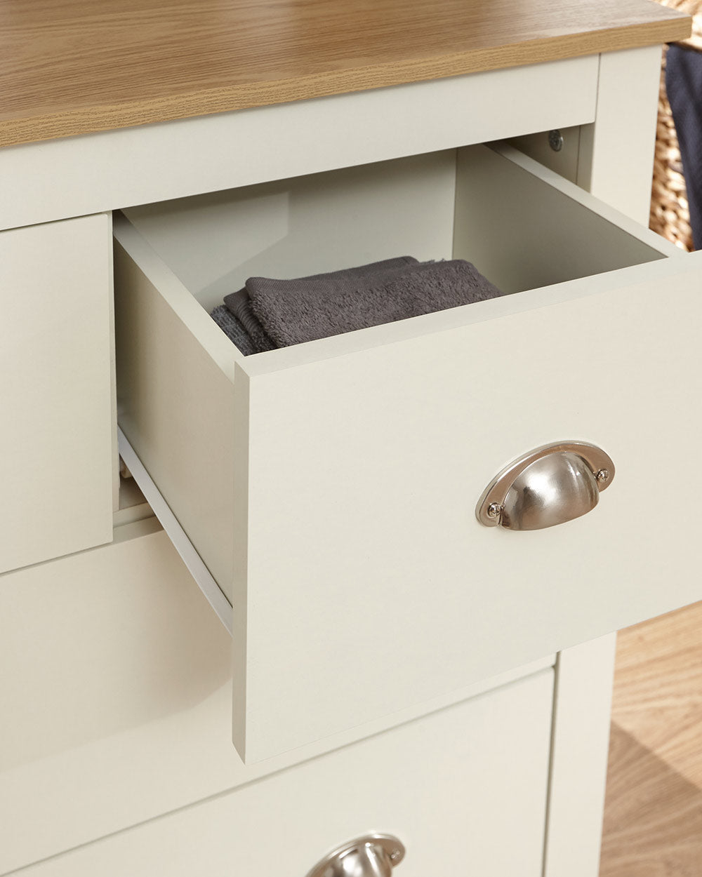 Lancaster 2 + 2 chest of drawers in cream with an oak effect top in a lifestyle setting in a bedroom with the drawer open with items inside
