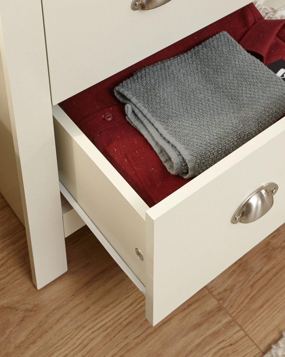Lancaster 2 + 2 chest of drawers in cream with an oak effect top in a lifestyle setting in a bedroom with the drawer open with items inside