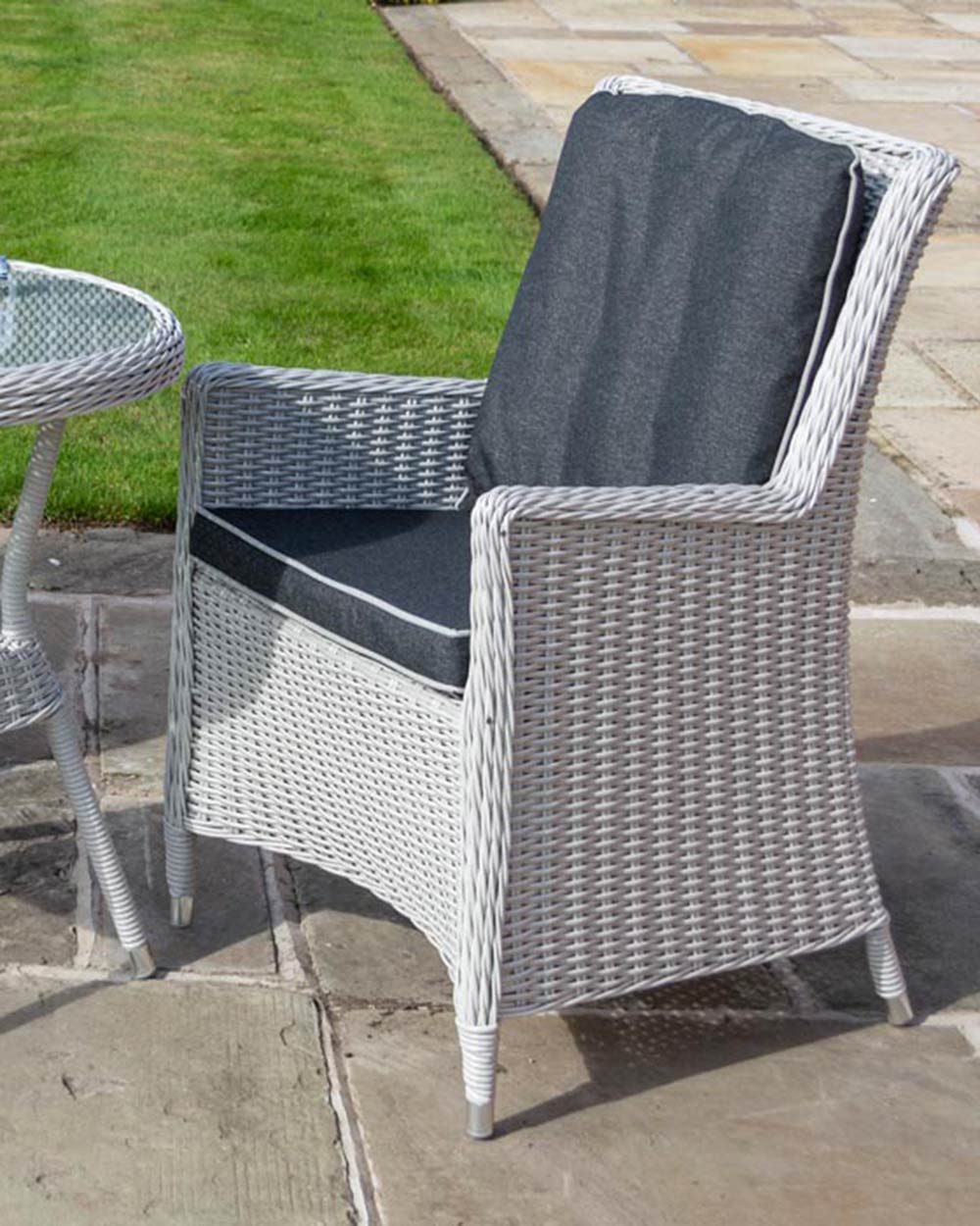Close up of one of the light grey rattan chairs with comfortable back and seat cushions