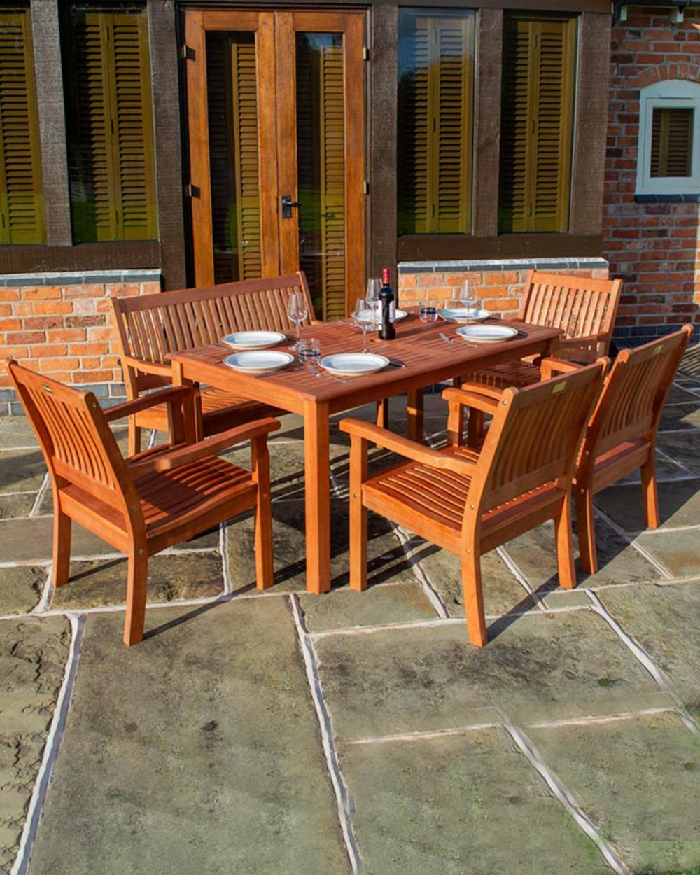 6 seater wooden garden furniture set photographed in a lifestyle scene. With table settings