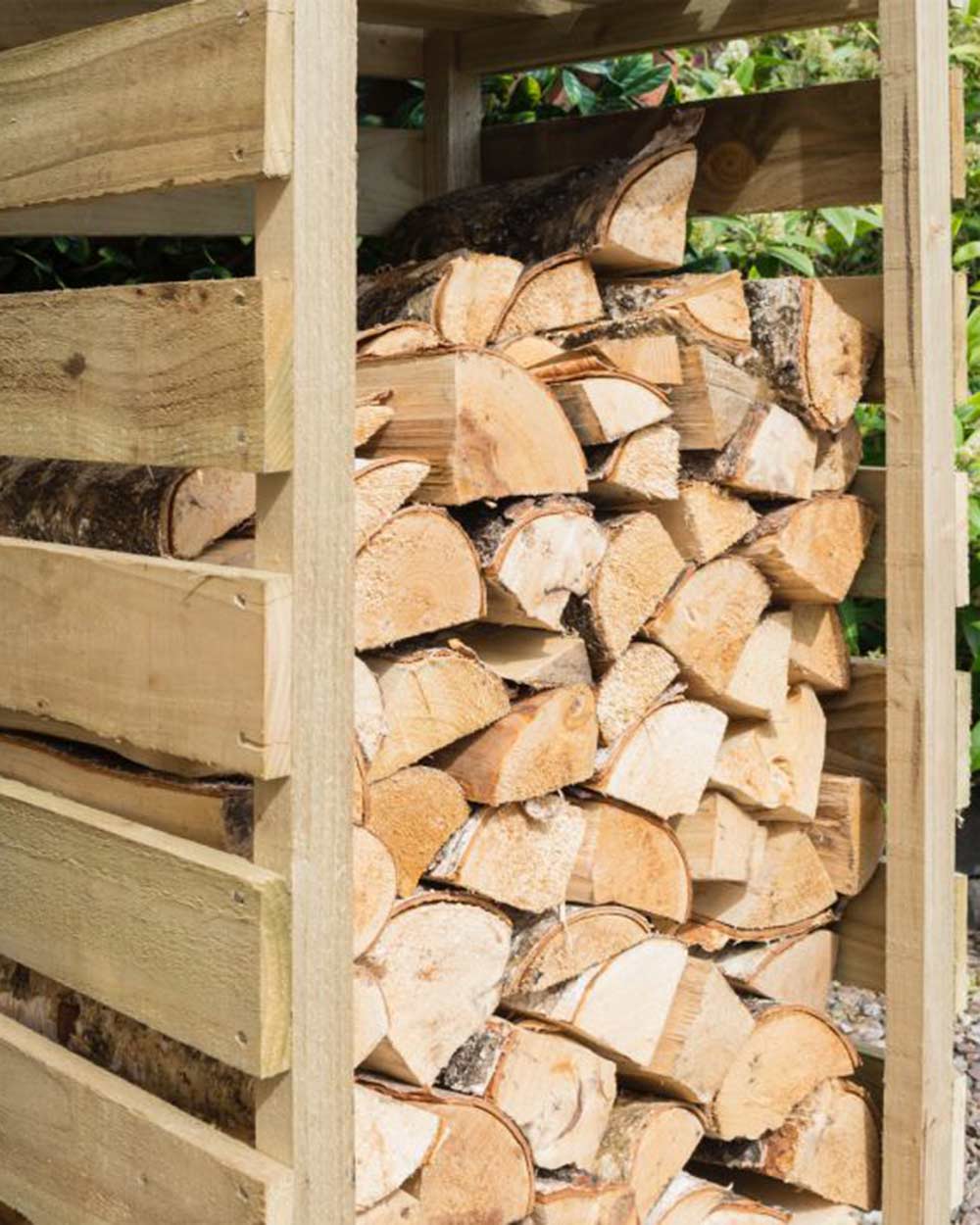 Slim log store narrow outdoor storage for wood kindling. Photographed in the garden with wood and kindling stored inside. Close up of the top of the bottom