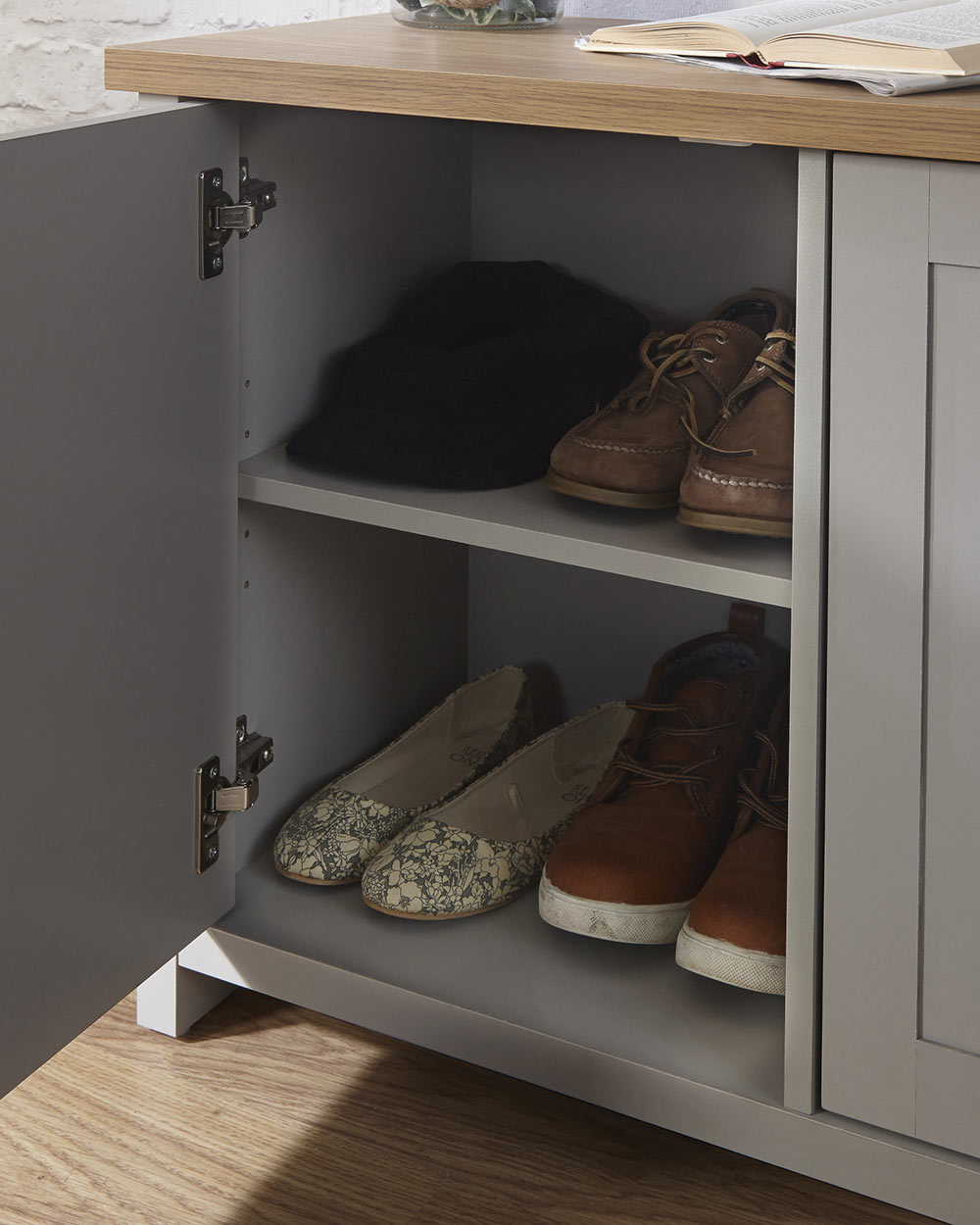 Lancaster shoe storage lifestyle inside a hallway setting. Grey with an oak effect top a close up of the door open and shoes inside