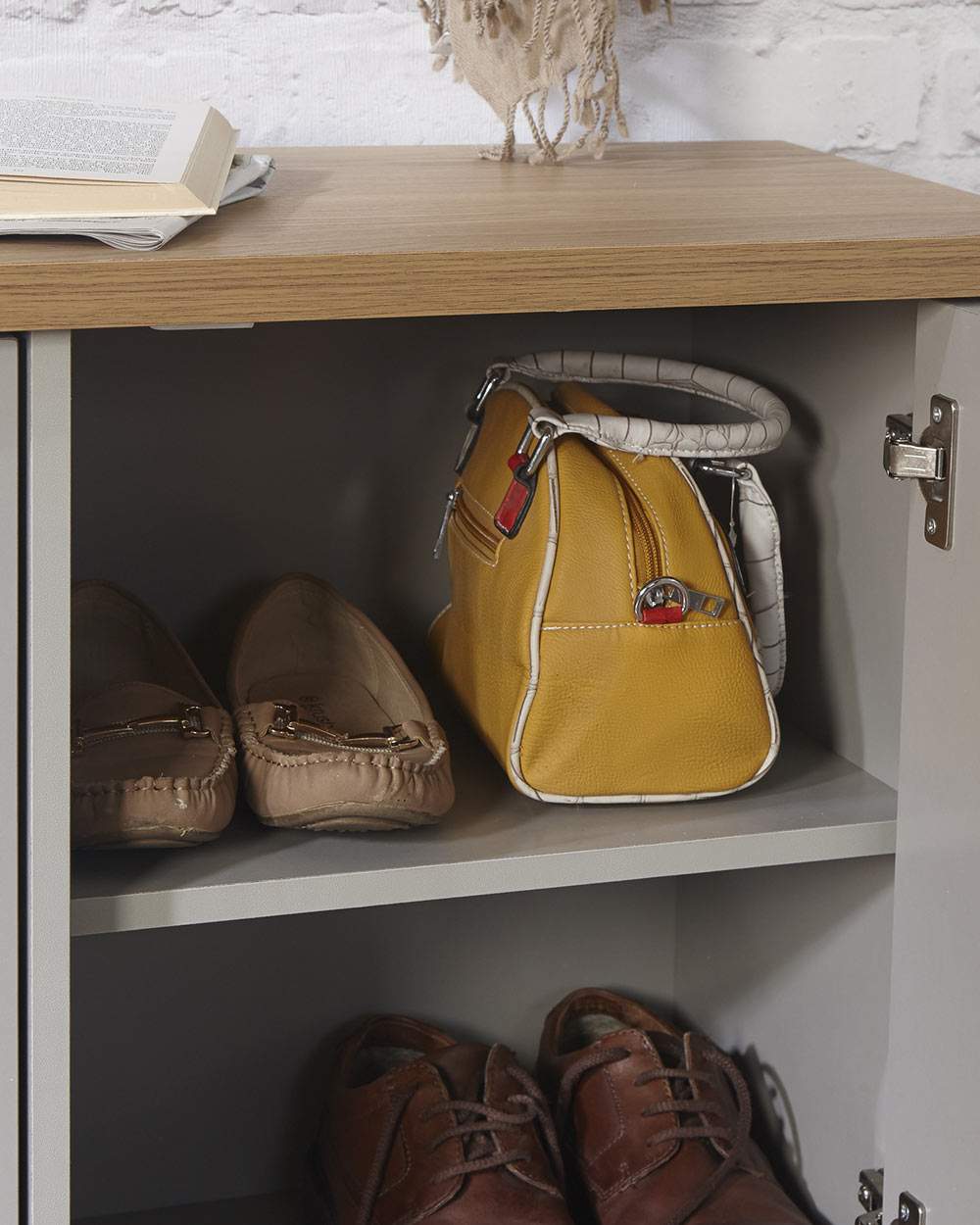Lancaster shoe storage lifestyle inside a hallway setting. Grey with an oak effect top a close up of the door open and shoes inside and a bag