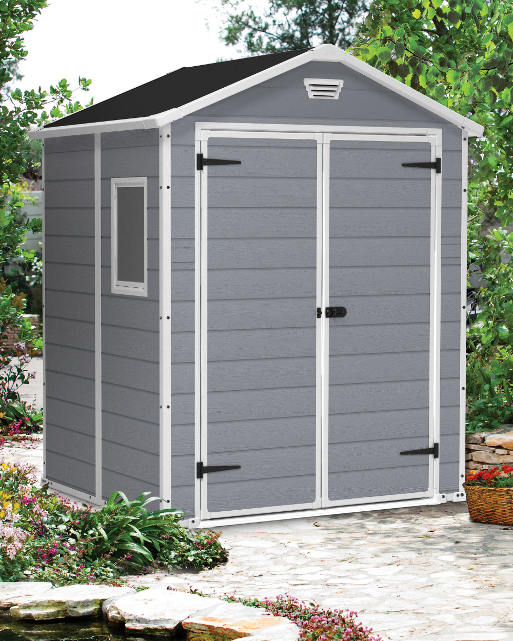 MANOR 6x5 GREY Shed Gray garden shed with a black roof on a patio with plants and flowers.